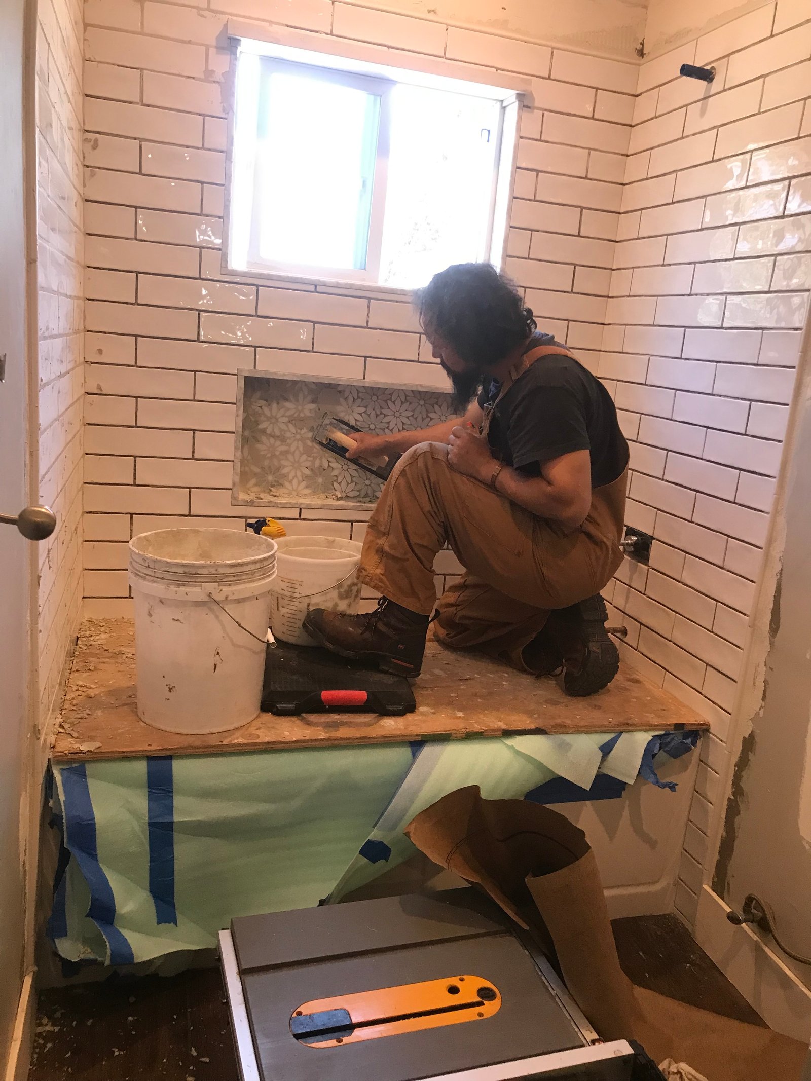 Craftsman applying drywall finish above the shower surround