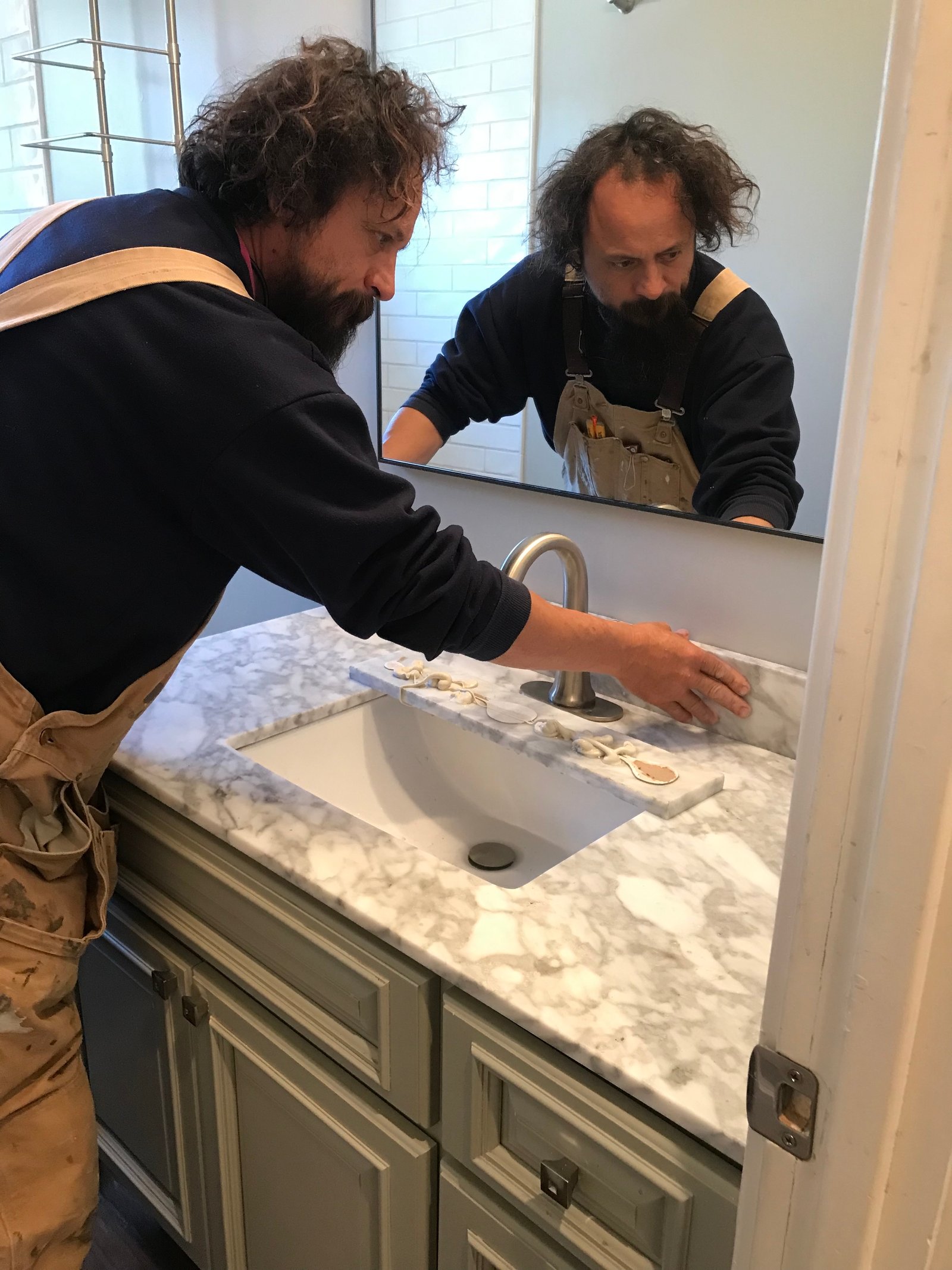 Installer holding marble trim in place along the backsplash