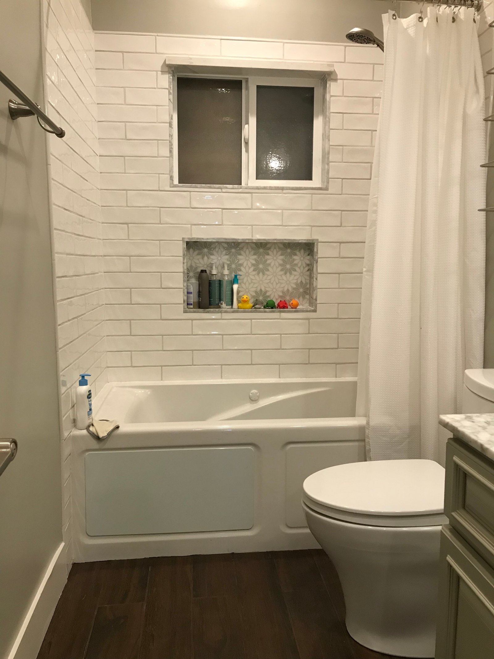 Installer seated on tub showcasing finished tile niche
